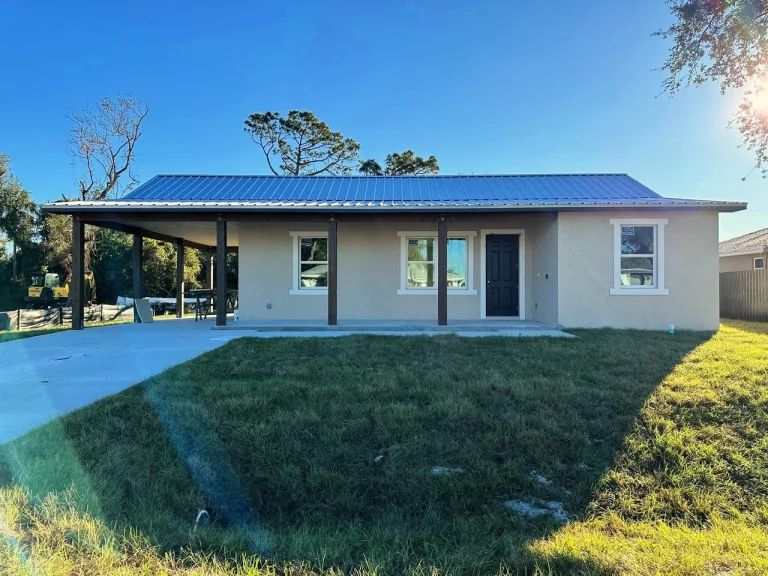 Newly built single-story home at 421 Chamber Street NW, Port Charlotte, with blue metal roof and carport
